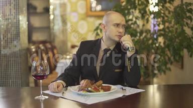 聪明迷人的秃头在高级餐厅独自品尝一杯红酒和切火鸡餐